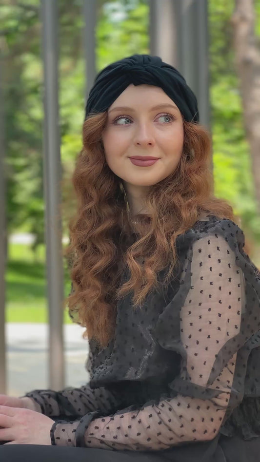 Femme souriante portant le turban Maison Dunel Ébène, assise sur un banc, style chic et décontracté