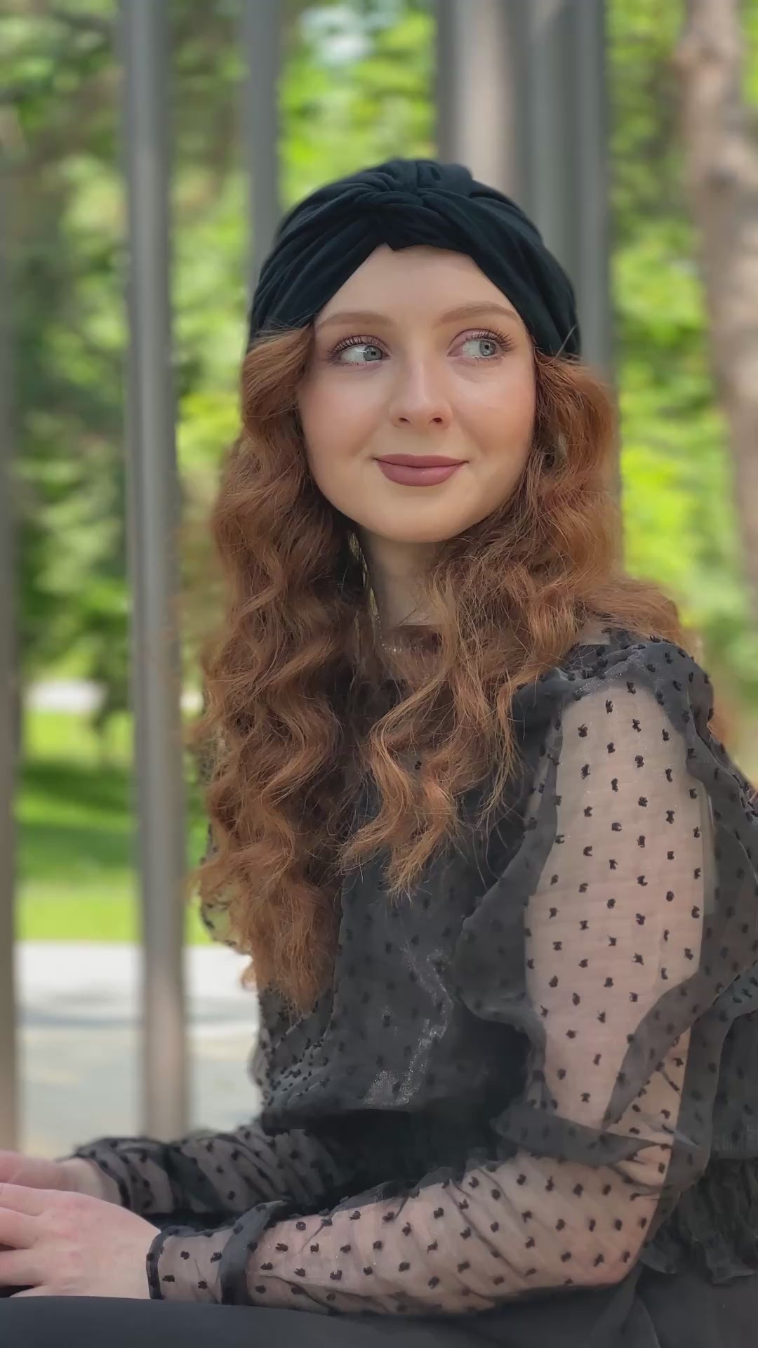 Femme souriante portant le turban Maison Dunel Ébène, assise sur un banc, style chic et décontracté